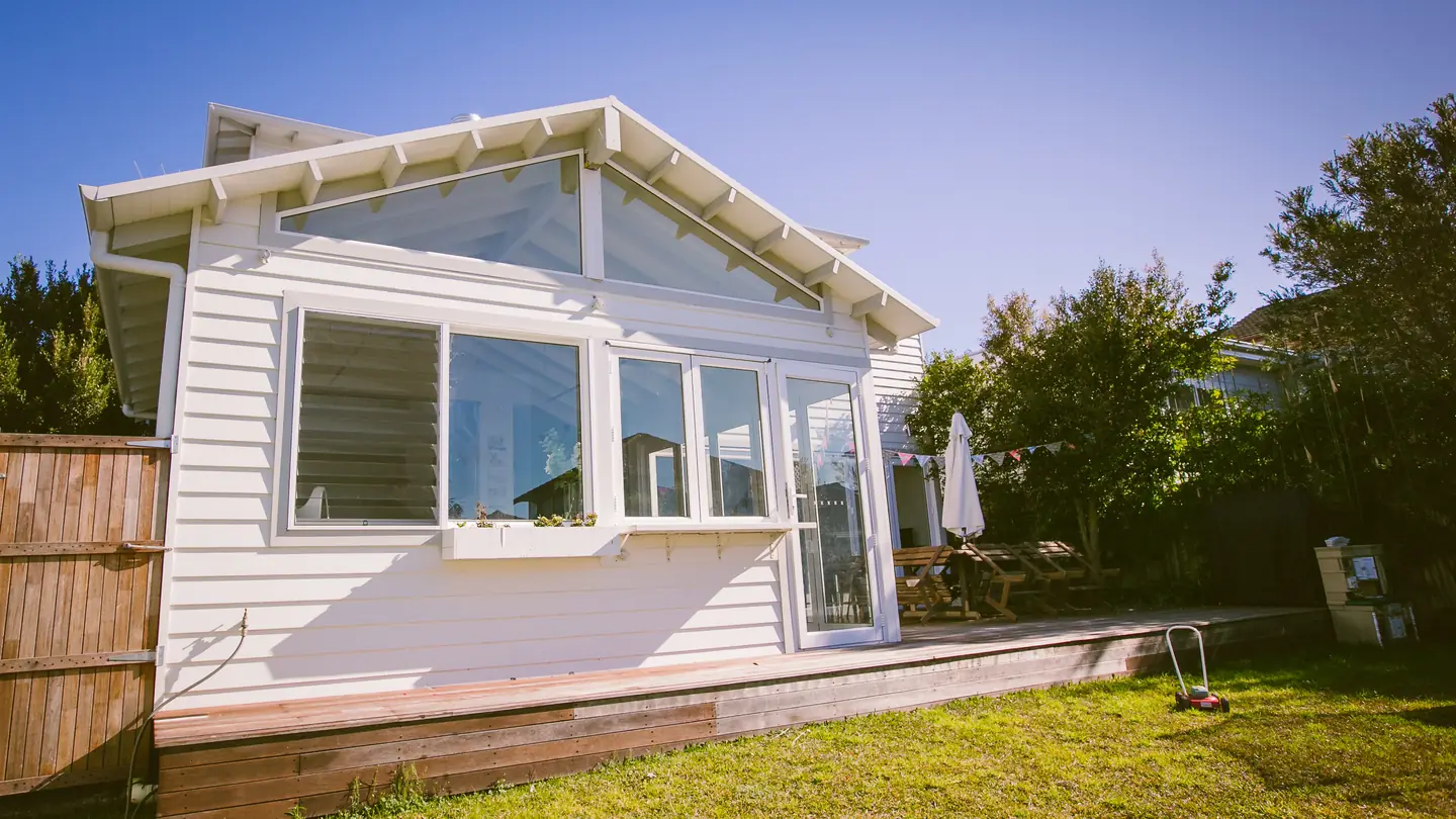 A weatherboard cottage with a raked-ceiling rear addition, seen from the back garden.