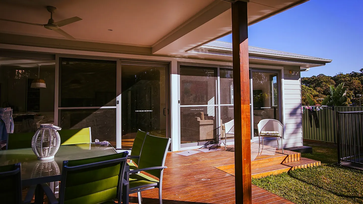 An alfresco area under a continuous roof, with a dining setting and glazed sliding doors to the interior.