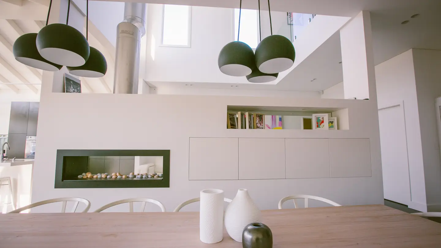 Dining table beside a linear gas fireplace in a raked-ceiling addition.