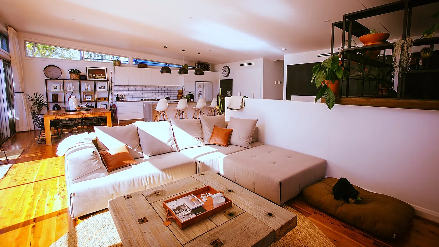 An open living room with a low modular sofa, open shelving and a band of high windows under a raked ceiling.